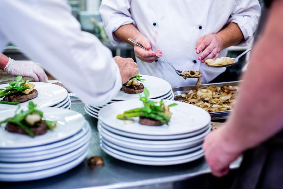 Chefs plating beef dishes in the kitchen